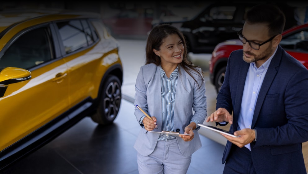 Two members of staff reviewing a report on a car dealership