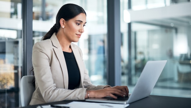 usinesswoman using a laptop at her desk in a modern office
