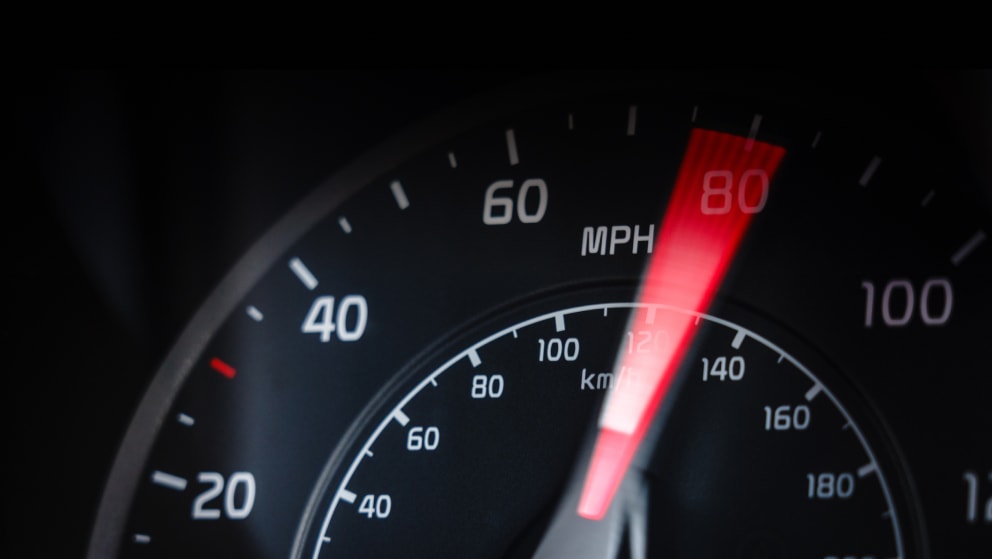 Motion blur as a car's speedometer shows the speed passing 80mph