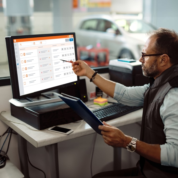 A man working at a computer in a car repair shop