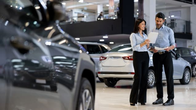 Two people in a car showroom, focused on a tablet