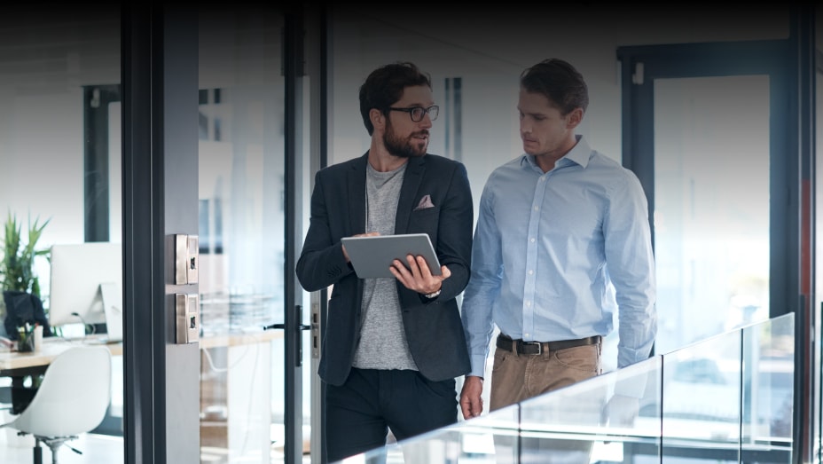 Two businessmen using a digital tablet together in an office