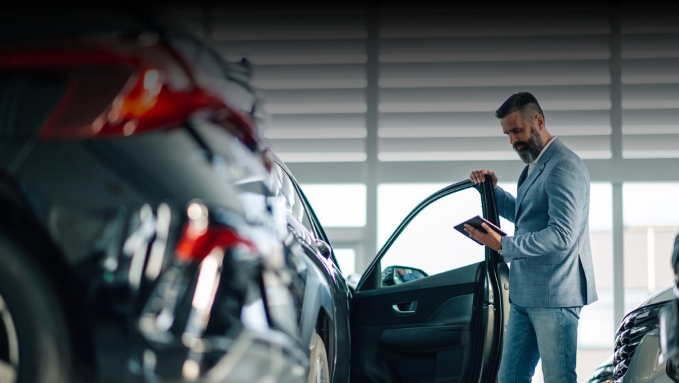 A man checks a car using a digital tablet