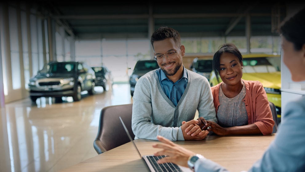 Young couple and car shop manager using laptop