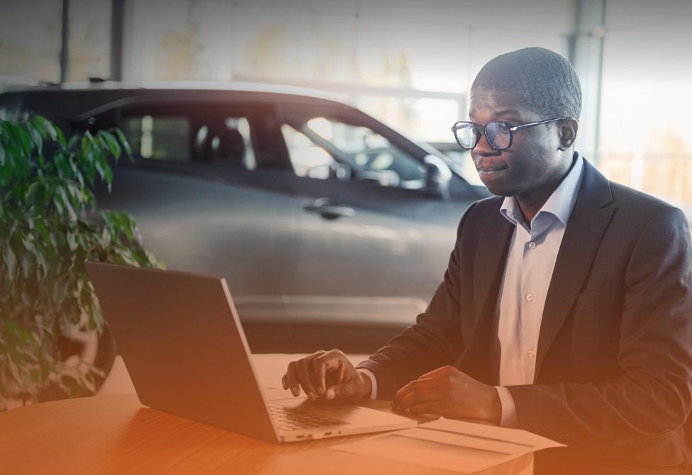 Office worker sits in auto repair shop at table with laptop computer