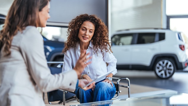 Manager explaining looking at tablet and explaining the car services to woman
