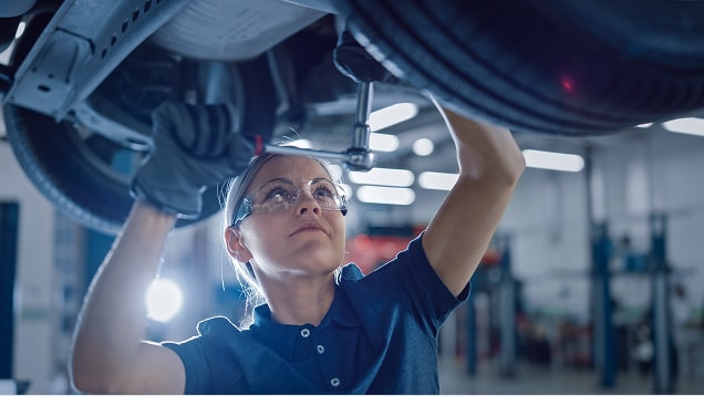 Female Mechanic Working Under Vehicle in a Car Service
