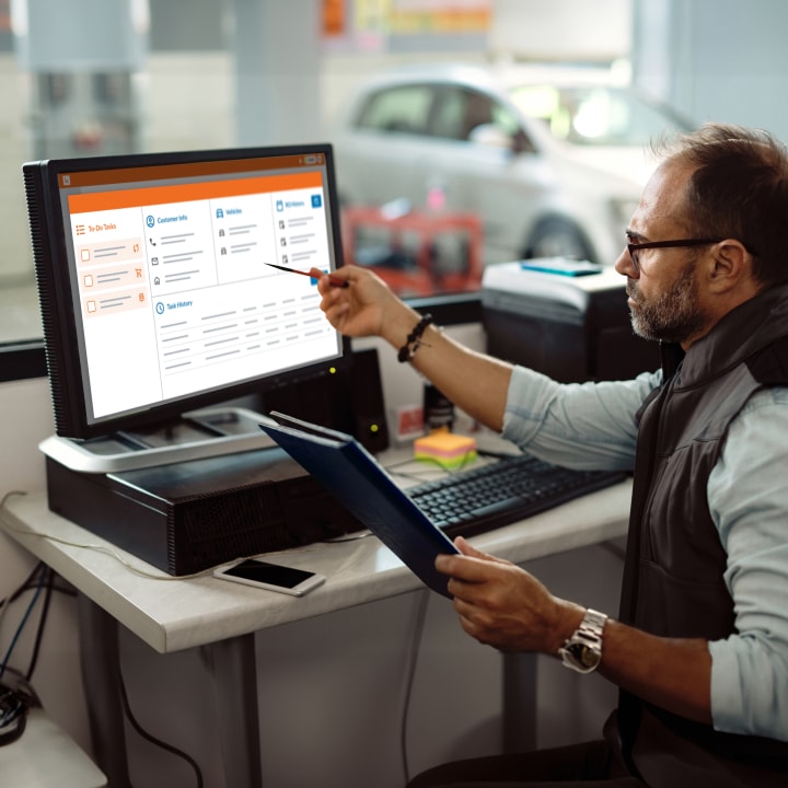 A man in a car repair shop working at a computer