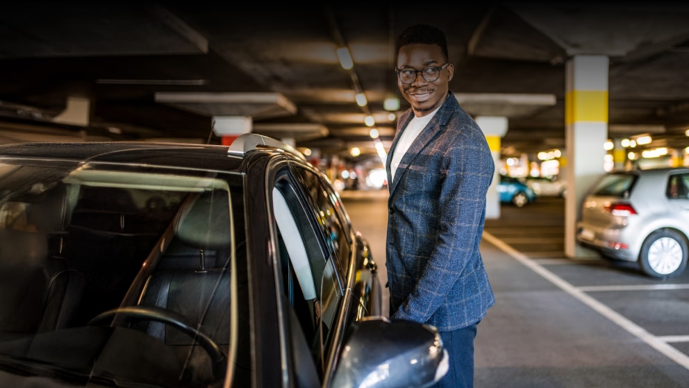 Happy businessman entering his car at car parking garage