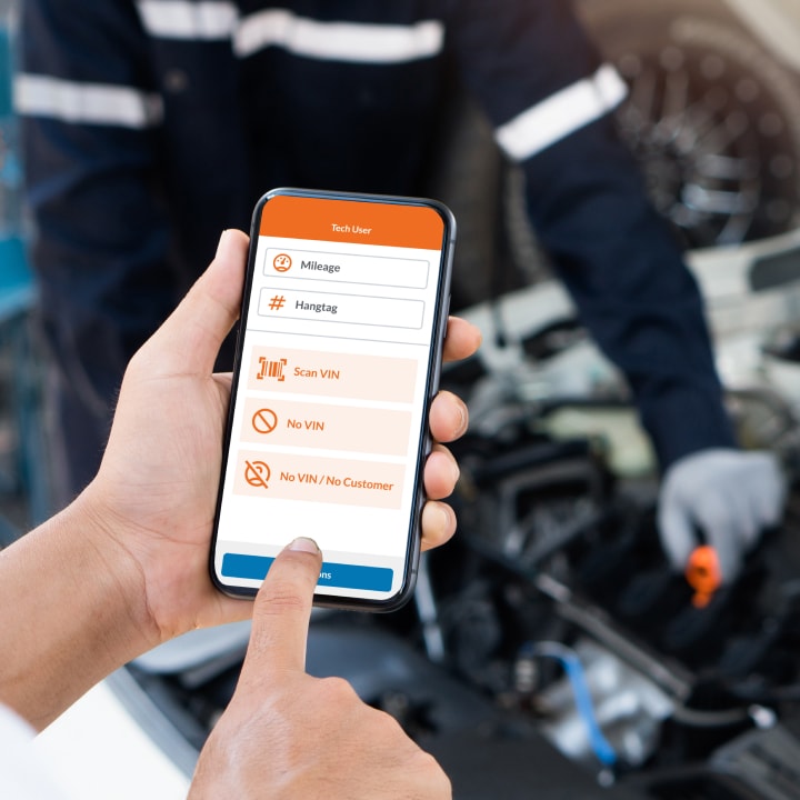A man inspects his car's engine while checking the ServiceCart feature