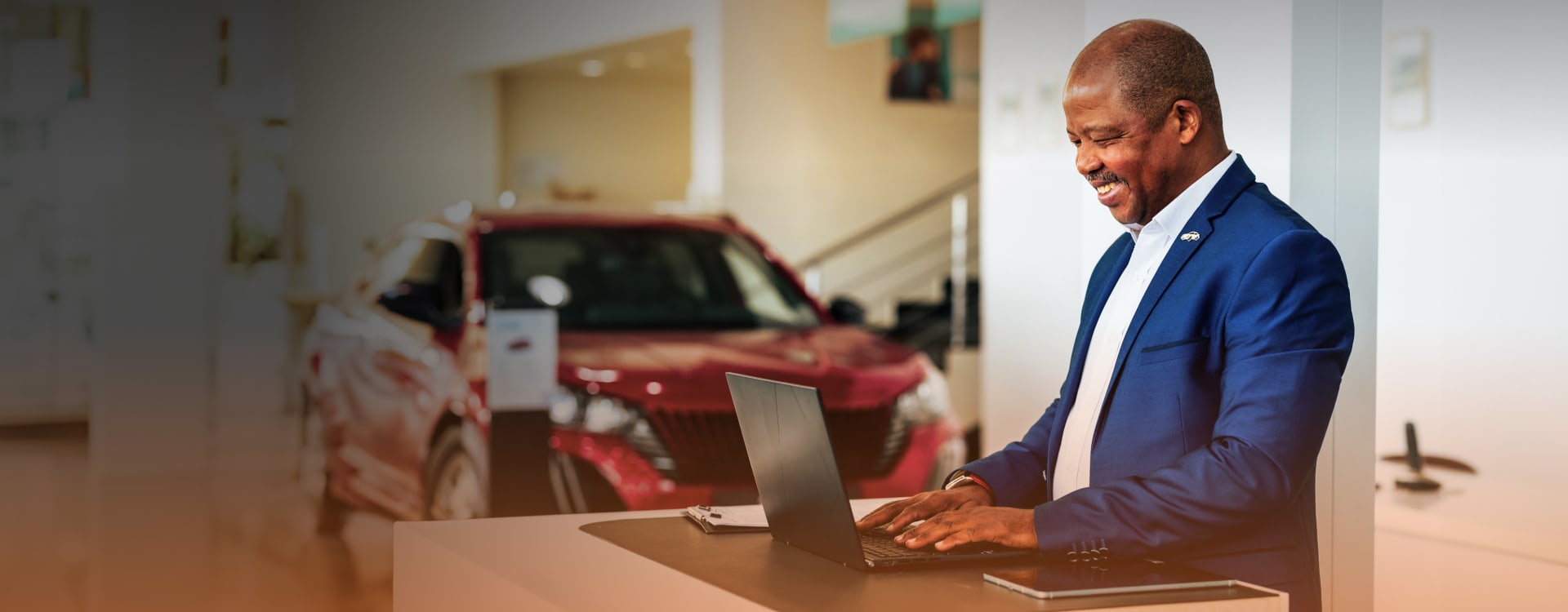 Car dealership worker at computer smiling