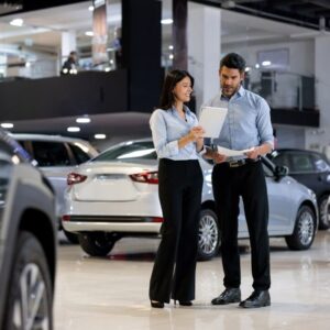 Two people in a car showroom, focused on a tablet