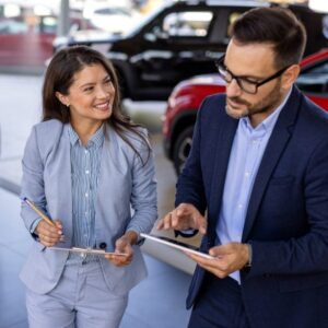 A man and woman are engaged with a tablet in a car dealership