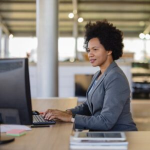 A woman at a car dealership, working on a computer at her desk